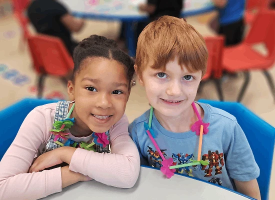 Two Children sitting at a table in a classroom.