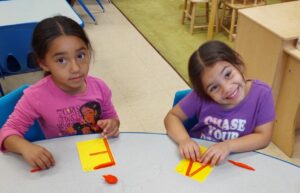 Two young children seated at a table playing with playdough