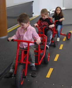 Preschoolers riding tricycles on indoor track