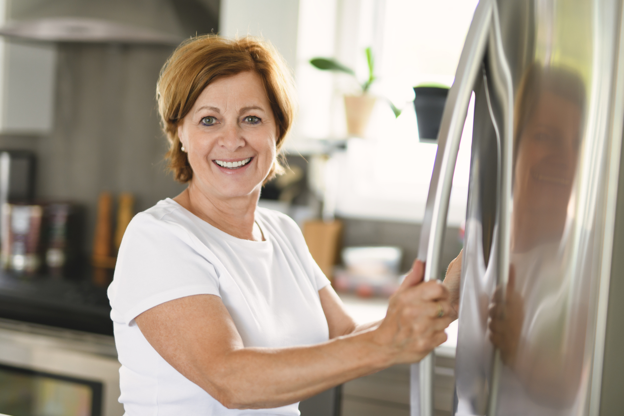Woman with her hand on a refrigerator-freezer door handle
