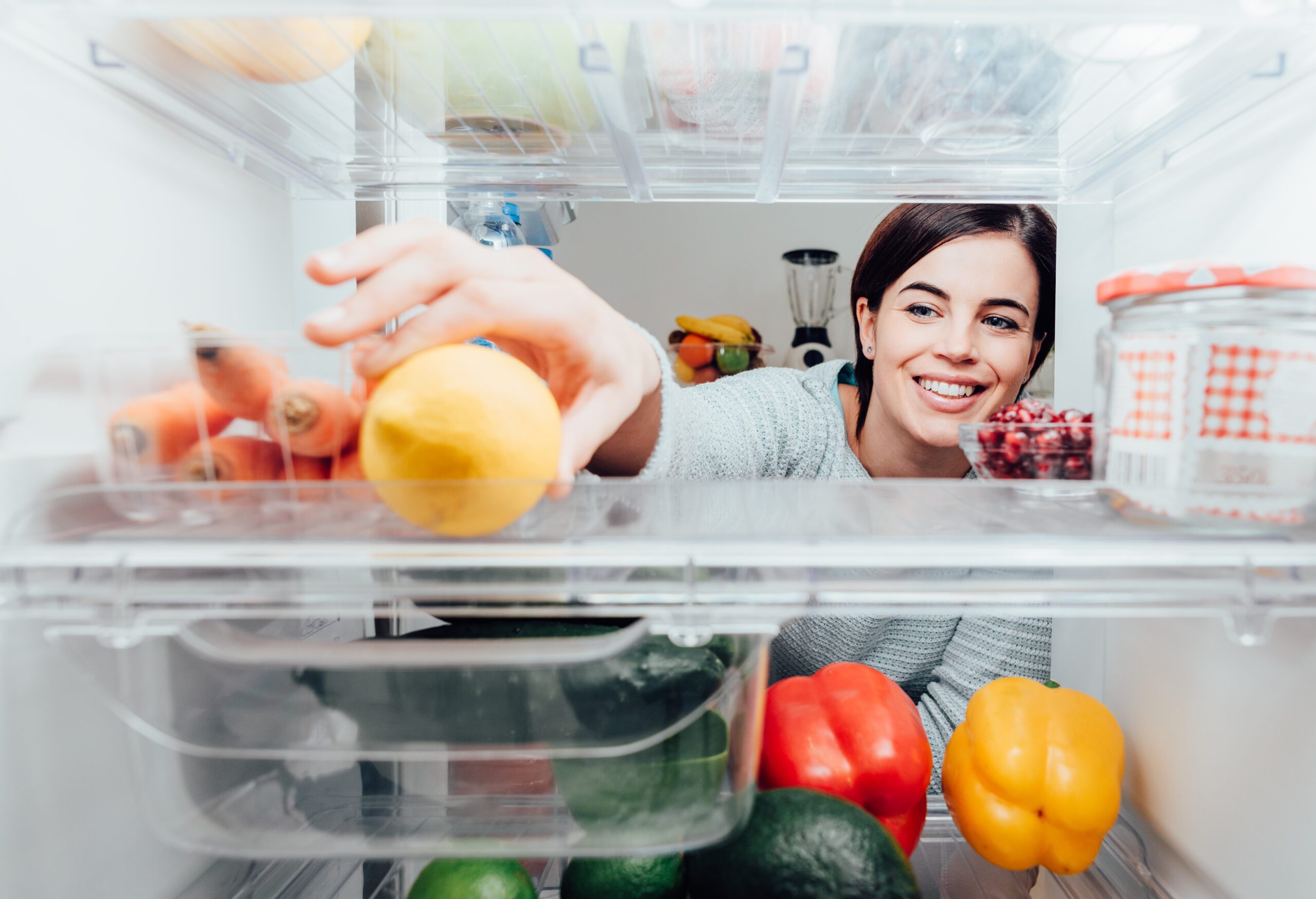 white woman reaching into refrigerator